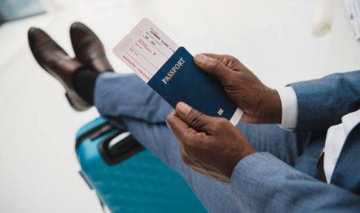Cropped image of African american man holding passport and fly ticket in hands